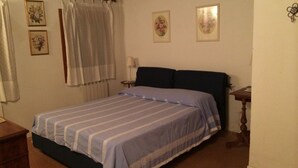 Un dormitorio con cama, mesita de noche, lámpara y cabecera de madera.