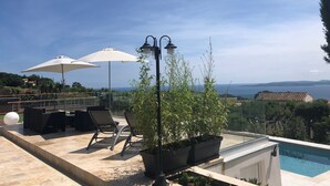 A rooftop terrace with outdoor seating, a pool, and a view of the sea.