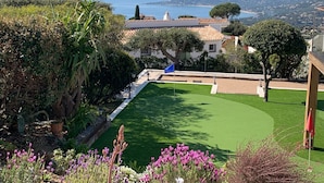 A golf course with a clear view of the sea and distant hills.