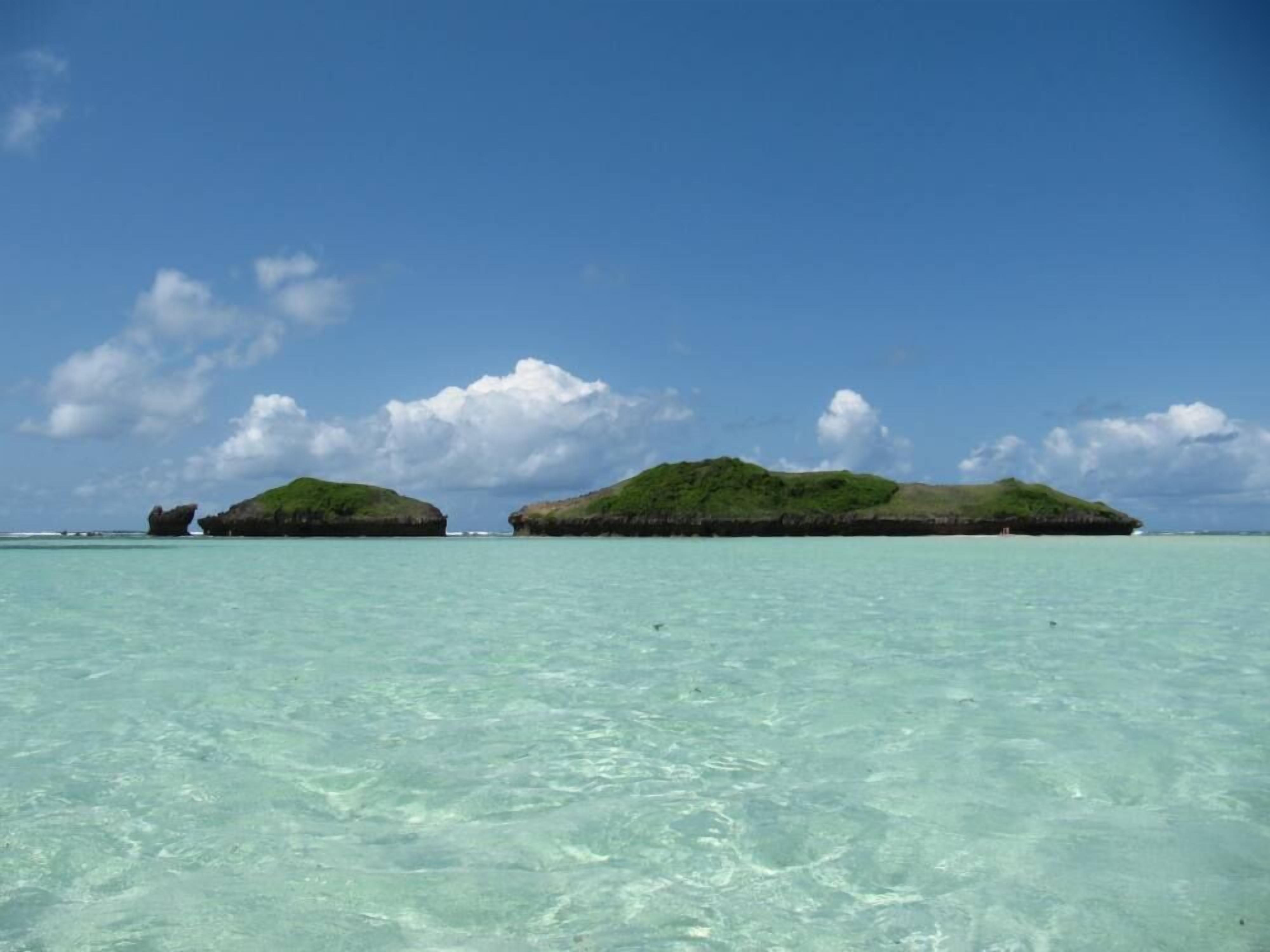 Mare turchese cristallino con due isole verdi all'orizzonte.