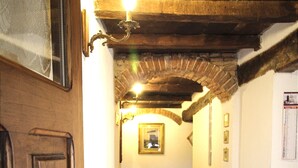 A narrow hallway with wooden doors and a tiled floor, leading to a room with a radiator and a framed picture on the wall.