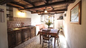 A rustic kitchen with wooden cabinets, a tiled backsplash, and a dining table with chairs.