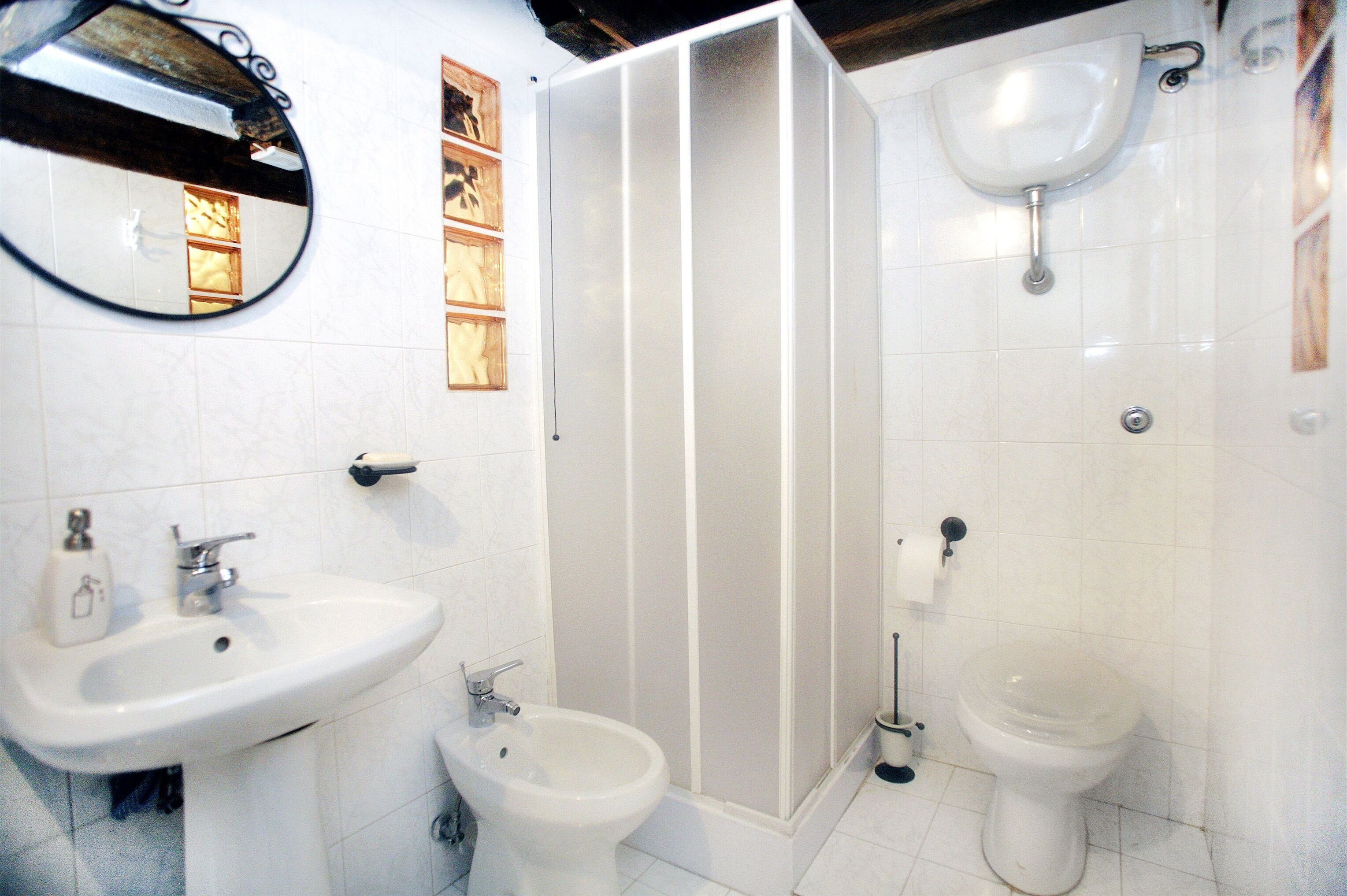 Een badkamer met een wastafel, bidet, toilet en douchecabine.