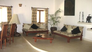 A living room with two sofas, a coffee table, a lamp, a potted plant, and a map on the wall. - Superior villa with garden / pool and personal service to 150mt sea (WATAMU)