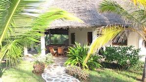A thatched-roof structure with a stone pathway leading to a wooden table and chairs. - Superior villa with garden / pool and personal service to 150mt sea (WATAMU)