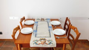 A dining table with a decorative runner, six chairs, and a white wall in the background. - APARTMENT IN VILLA 200 METERS FROM THE SEA WI FI CAR RENTAL UC (castellammare del golfo)
