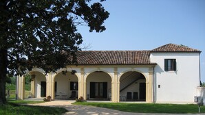 Un edificio con tejado de tejas, múltiples arcos y un camino de grava que conduce a la entrada.