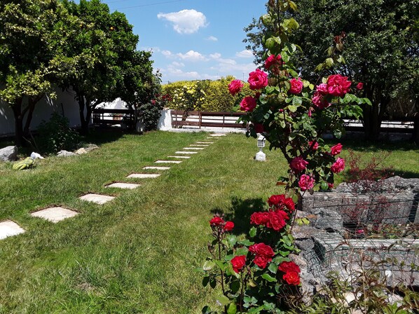 Un sentier de jardin, ponctué de pierres plates, mène à un belvédère blanc.