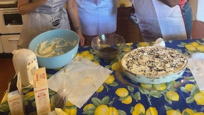 Trois personnes se trouvent dans une cuisine, et une table avec un gâteau est visible au premier plan.