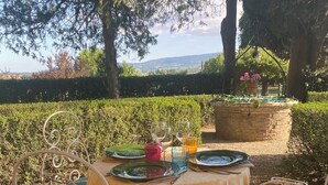 Un espace de restauration en plein air avec une table dressée pour deux personnes, entourée de chaises en métal dotées de coussins verts.