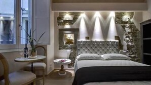 A bedroom with a large bed, a small round table with a chair, a stone accent wall, and a stone fireplace. - Studio in Piazza Signoria - Internet WiFi, Air Conditioning New 2011 (Firenze)