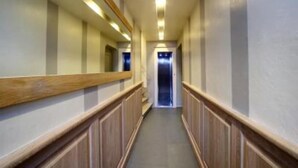 A hallway with wooden paneling, a central elevator, and a mirrored wall. - Studio in Piazza Signoria - Internet WiFi, Air Conditioning New 2011 (Firenze)