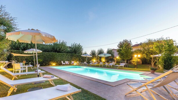 A swimming pool with lounge chairs and umbrellas, surrounded by a hedge and trees. - Apartment "Yellow", with pool, Villa Gabriella (Lucca)