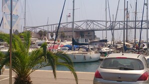Ein Yachthafen mit vertäuten Booten, im Hintergrund eine Brücke und im Vordergrund ein Auto.