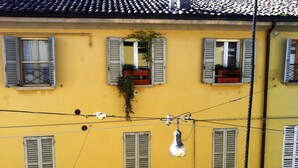 Un edificio giallo con numerose finestre, alcune dotate di persiane, e cavi elettrici visibili.