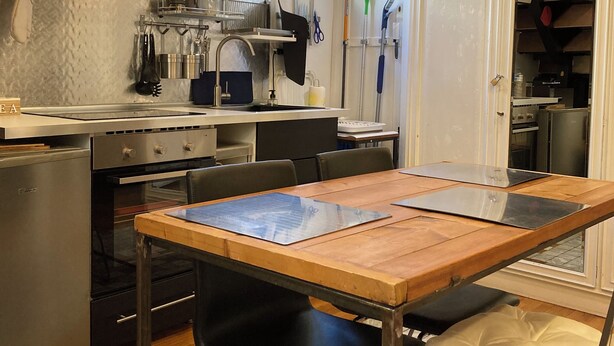 Una cucina moderna con elettrodomestici in acciaio inossidabile, un tavolo in legno e una sedia nera.