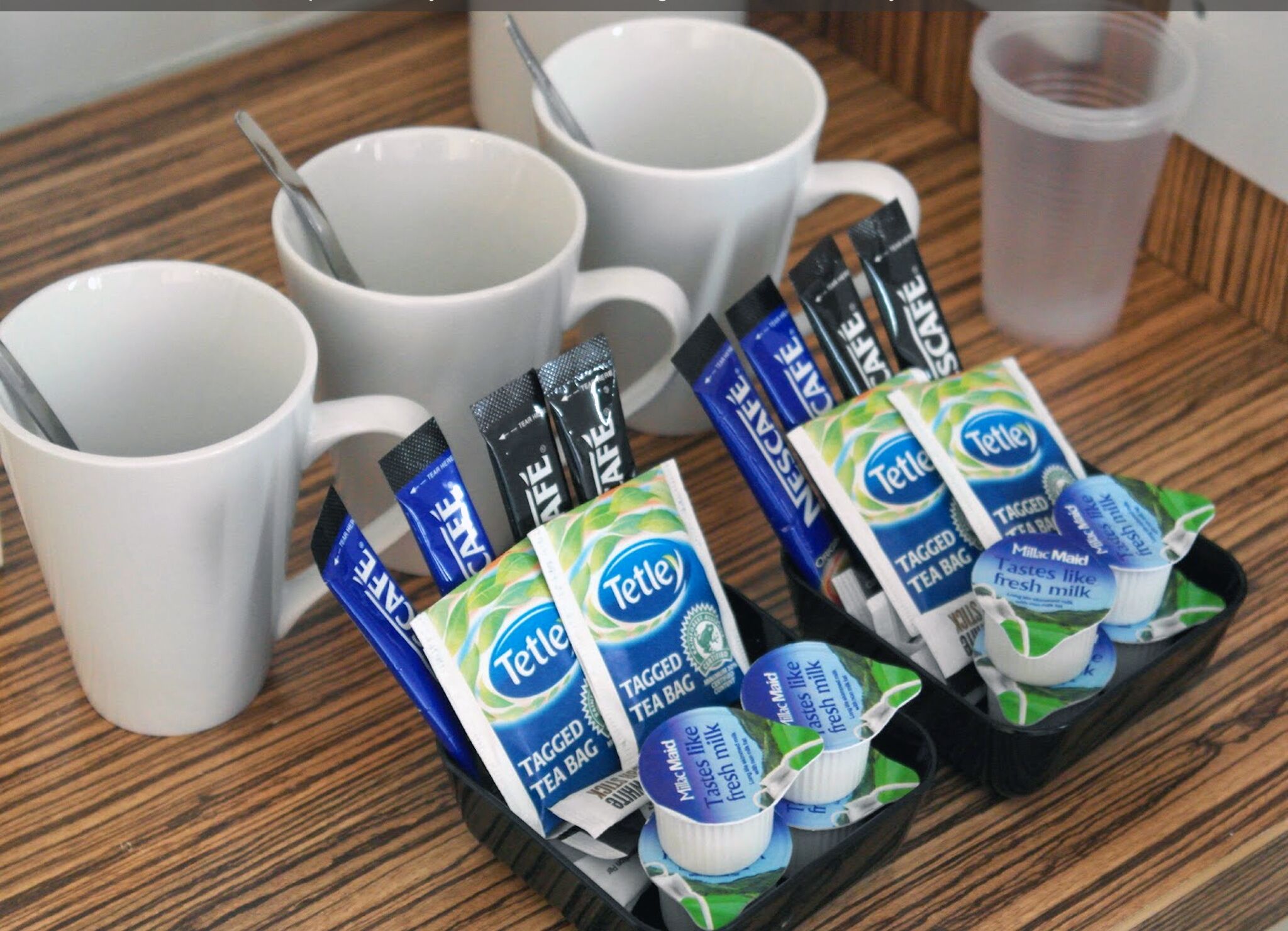 A tray with Tetley tea bags and a cup of tea on a wooden table.