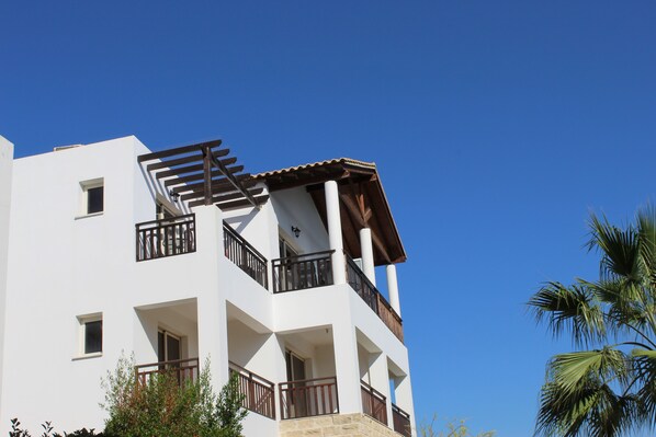 A multi-story building with balconies, windows, and a clear blue sky.