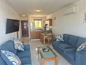 Una sala de estar con televisor, sofás y una mesa de centro.