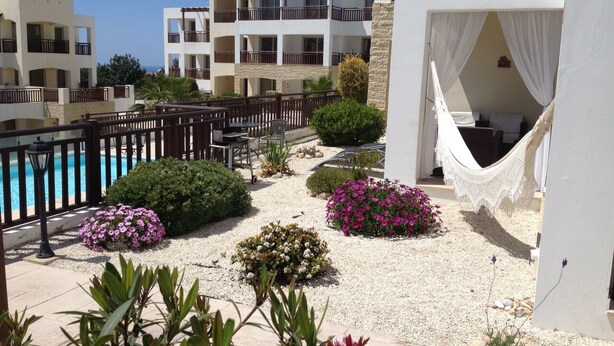Un patio de hotel con piscina, varios balcones y diversas plantas.
