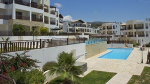 Un hotel de varios pisos con balcones, una piscina y un sendero de piedra.
