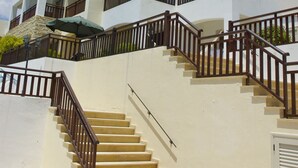 Un hotel de varios pisos con una escalera central, balcones y una pared de piedra.