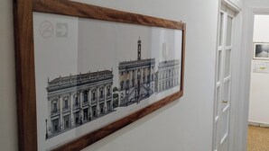 A hallway with a framed architectural drawing on the wall, a door, and a few framed pictures on the wall.