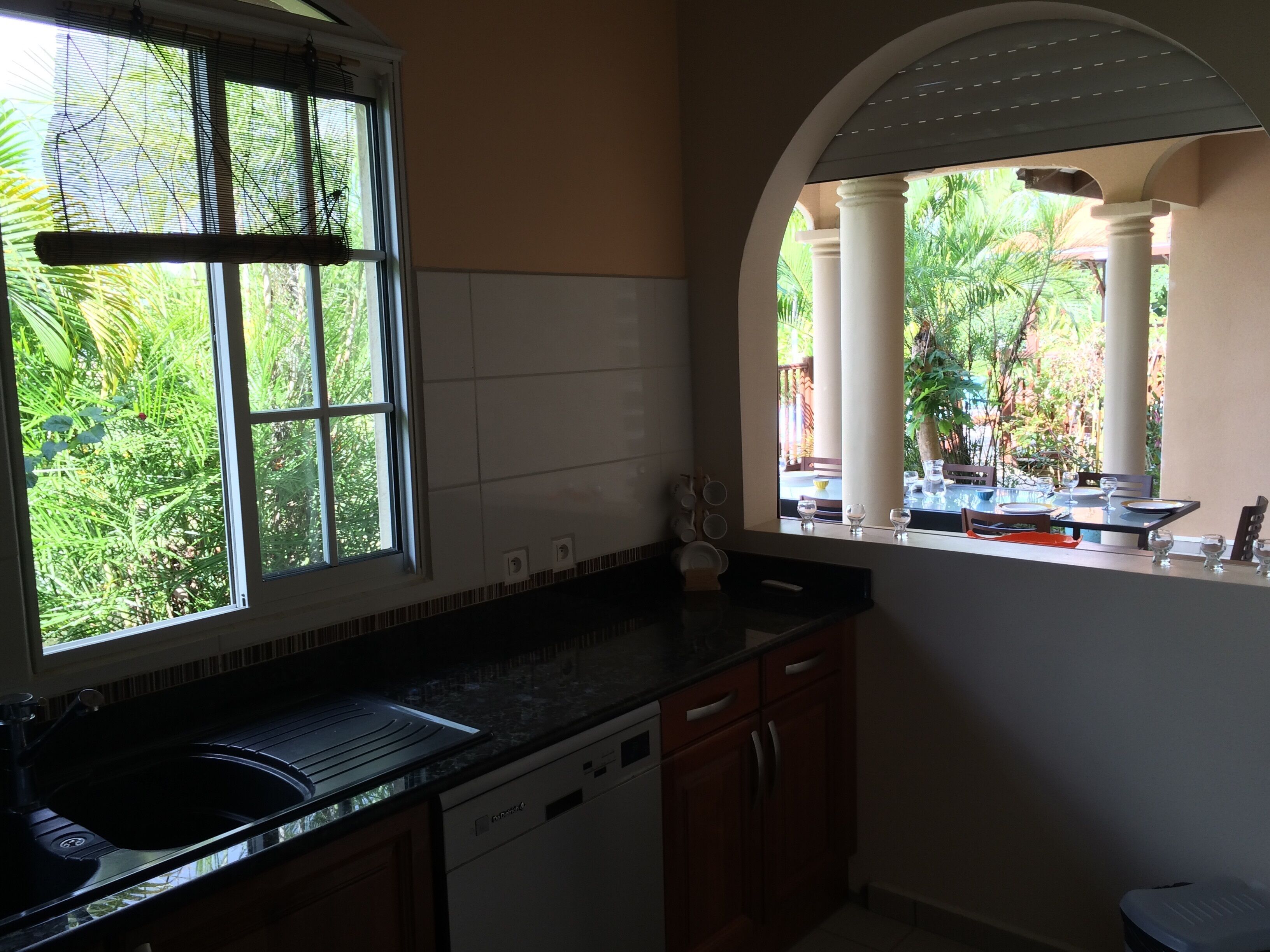 A kitchen with a window overlooking a garden, a sink, and cabinets.