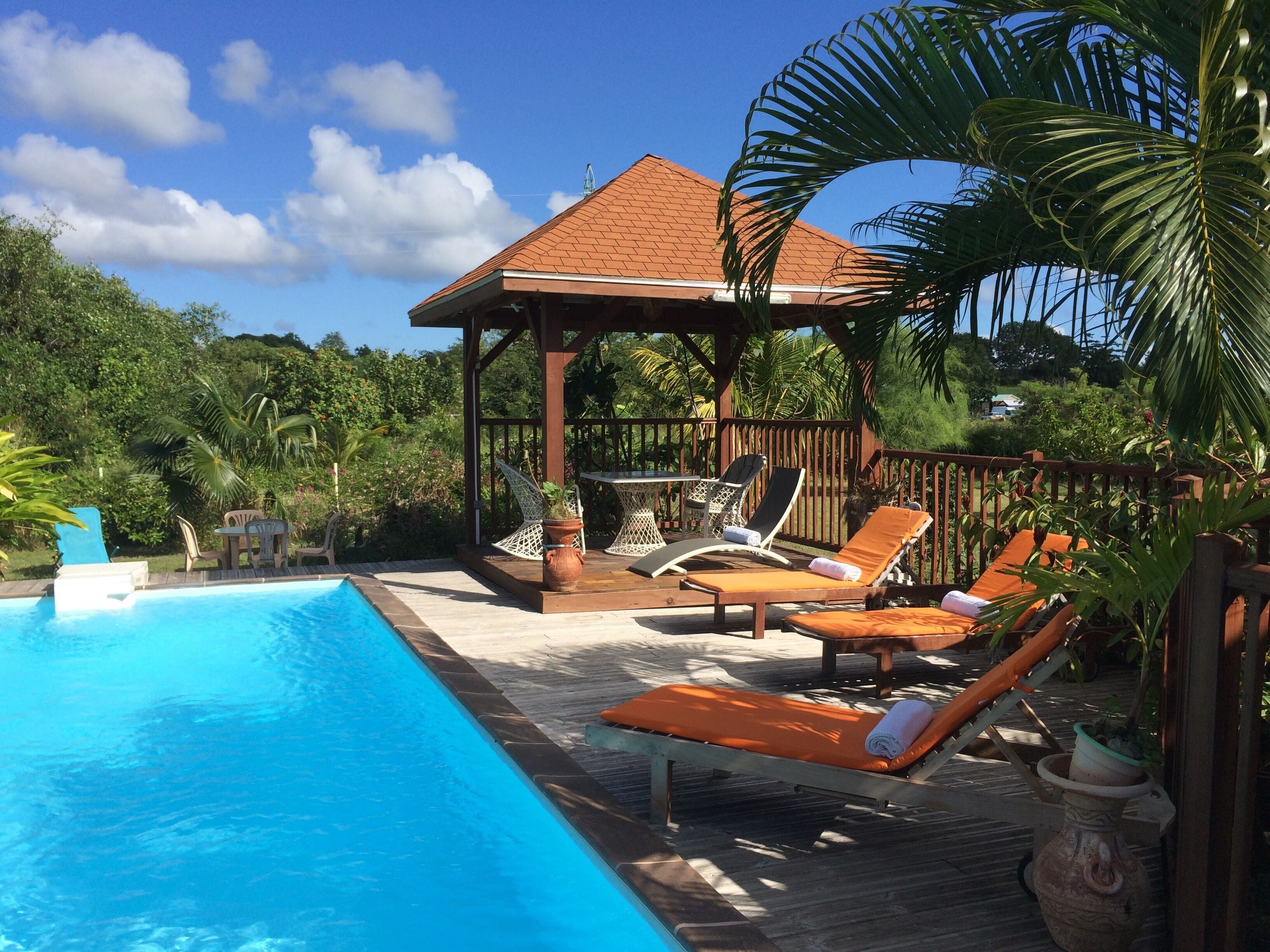A pool area with lounge chairs and a gazebo.