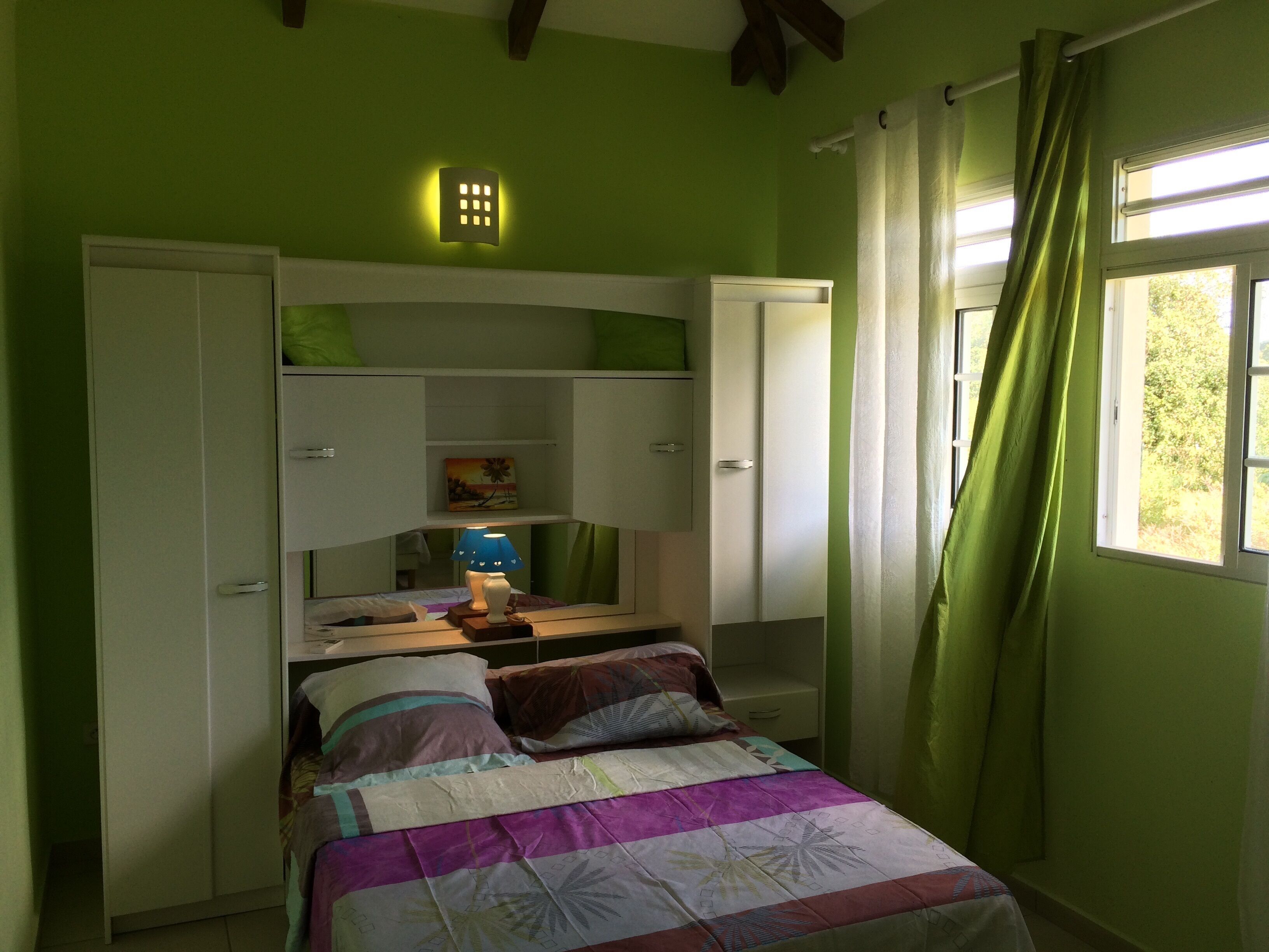 Een slaapkamer met een bed, een bureau en een kledingkast.