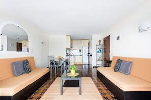 A living room with two sofas, a coffee table, and a dining area with a table and chairs.