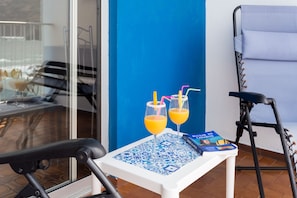 A table with two glasses of orange juice, a magazine, and a chair.