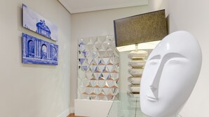 A hallway with a glass display case, a white bust sculpture, and two blue paintings on the wall. - Top Design Apartment at OPERA Metro station (Royal Theater) / HIGH SPEED WiFi (Madrid)