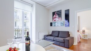A modern living room with a grey sofa, a glass coffee table, and a bowl of strawberries. There are two wine glasses on the table. - Top Design Apartment at OPERA Metro station (Royal Theater) / HIGH SPEED WiFi (Madrid)