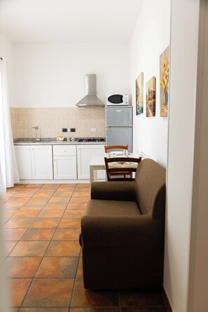 Cozy living space with a kitchenette, sofa, dining table, and microwave, perfect for a compact retreat.