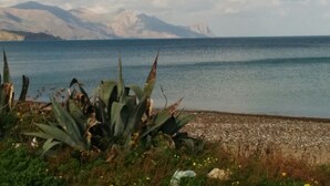 Un paysage côtier offrant une vue dégagée sur la mer et les montagnes lointaines.