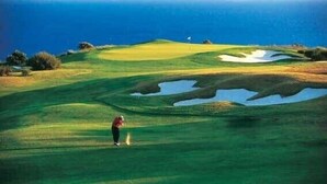 Un parcours de golf avec un drapeau, des bunkers de sable et un obstacle d’eau.