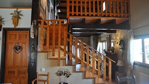 Eine Holztreppe mit Geländer, eine Tür mit Herzdekor und eine Wand mit verschiedenen Gegenständen, darunter eine Lampe und ein hängendes Ornament.