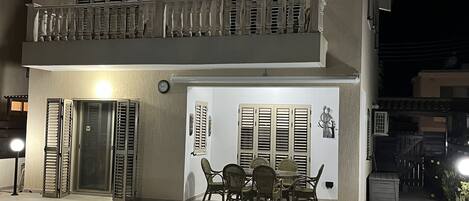 Un edificio de dos pisos con balcón, piscina y mobiliario exterior.