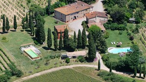 Vista aérea de una propiedad con un edificio grande, una piscina y un viñedo.