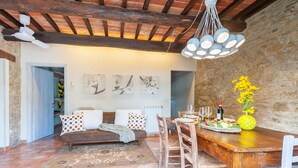 Una sala de estar acogedora con una mesa de comedor de madera, un sofá con cojines estampados y una pared de piedra.