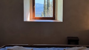 Une pièce dotée d’une petite fenêtre donnant sur un paysage composé d’arbres et de montagnes.