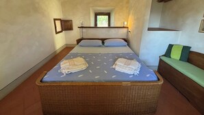 Une chambre avec un grand lit, un banc en bois et une petite fenêtre.
