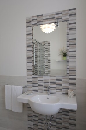 A bathroom with a white sink, a mirror, and a shower. - LA TERRAZZA – Wifi, amazing location and terrace! (Lucca)