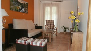 A living room with a sofa, armchair, ottomans, a painting, a lamp, and a vase with flowers. - Enjoy your complete rural house in Camporrotuno, Aínsa Sobrarbe (Camporrotuno)