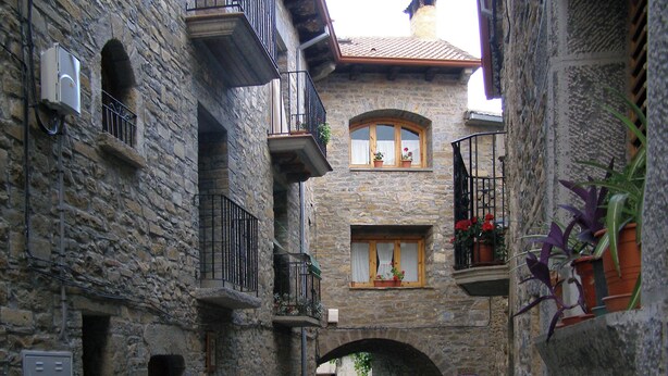 A narrow stone building with multiple balconies, a small archway, and potted plants. - Enjoy your complete rural house in Camporrotuno, Aínsa Sobrarbe (Camporrotuno)
