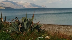 Un paysage côtier offrant une vue dégagée sur la mer et les montagnes lointaines.