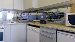Una cocina con armarios blancos, encimera de granito, microondas y lavavajillas.