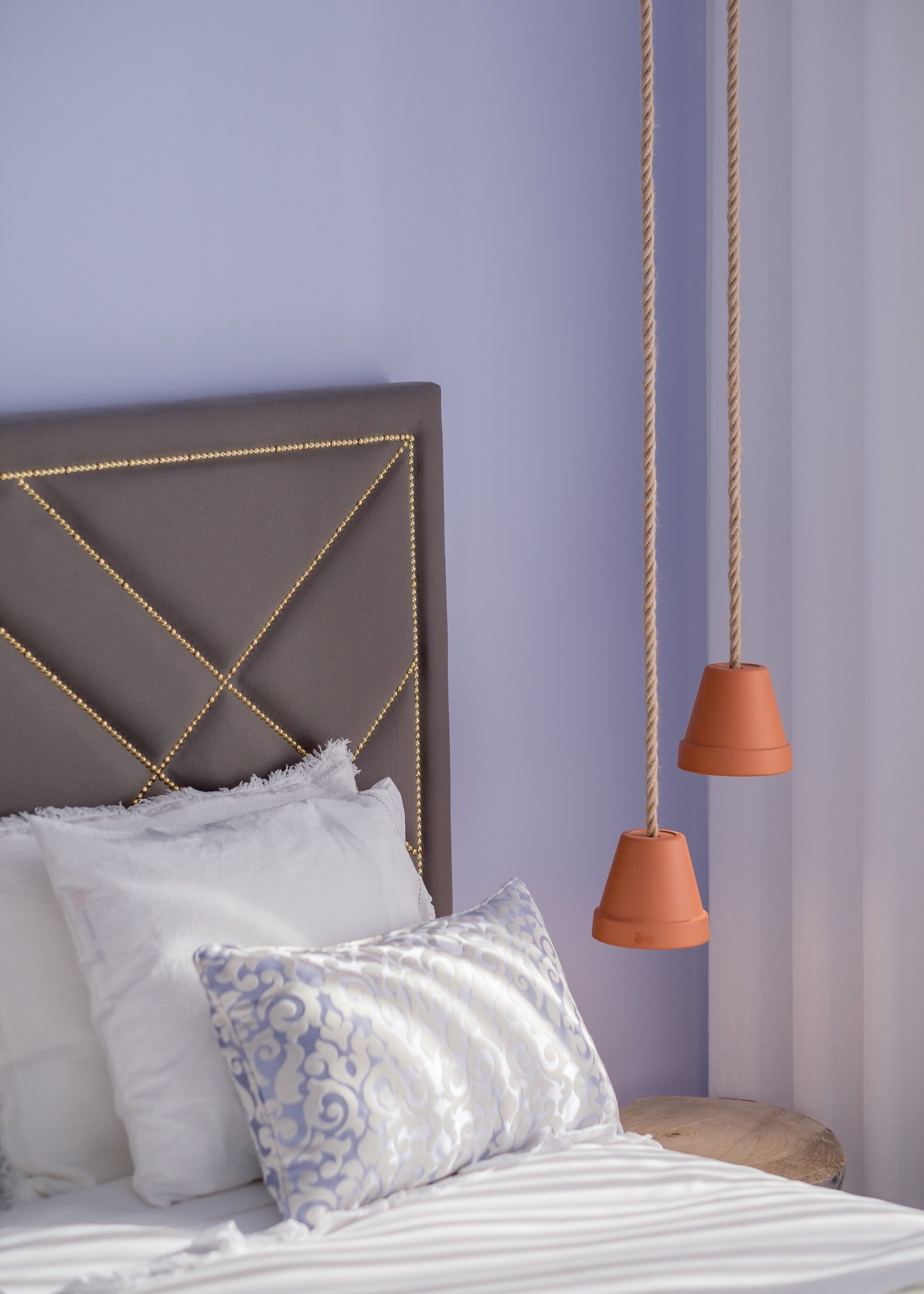 A bed with a headboard, pillows, and a hanging light fixture.