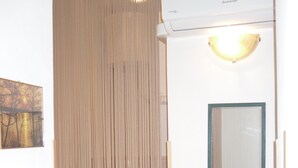 A room with a vertical striped partition, a mirror with a green frame, and an air conditioning unit. - NEAR THE SEA AND AWAY FROM NOISES (alcamo marina)